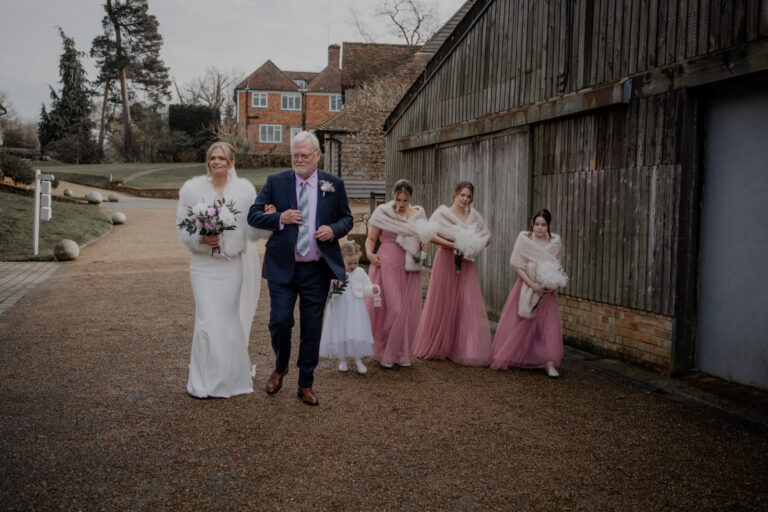 Bride arriving with bridesmaid and father at wedding ceremony.