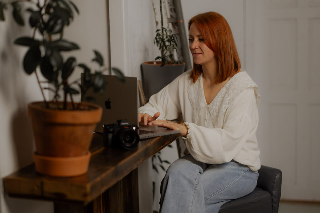 Portrait of Abby, North East Wedding Photographer at her laptop editing her wedding gallery.
