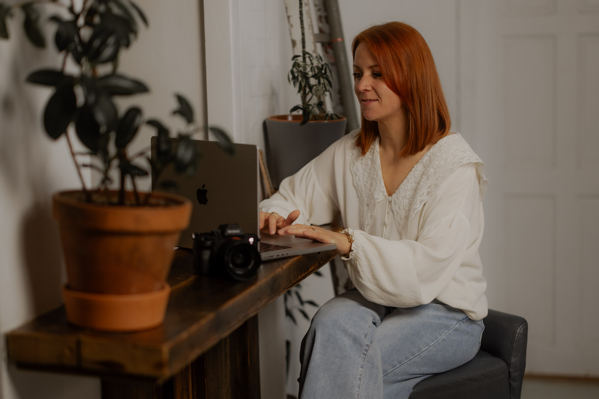 Portrait of Abby, North East Wedding Photographer at her laptop editing her wedding gallery.